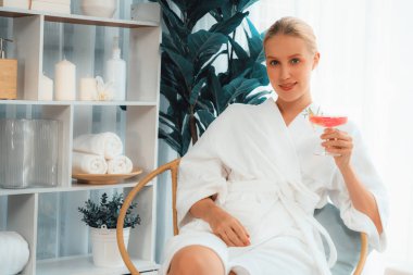 Güzellik ya da vücut bakımı güzellik salonu yaşam tarzı konsepti. Bornoz giyen bir kadın lüks otel kaplıcalarında ya da tatil odasında içkiyle rahatlıyor. Tatil ve boş zaman rahatlığı. Sessiz.