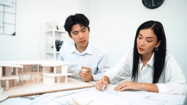 Profesyonel erkek mühendis ev modelini cetvel kullanarak ölçerken güzel bir kooperatif iş arkadaşı plan üzerinde yazarak birlikte çalışıyor. Yaratıcı tasarım ve takım çalışması. - Yakın çekim. Tertemiz..