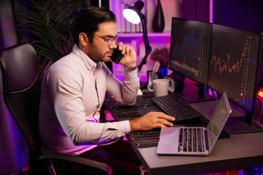 Tüccar akıllı işadamı komisyoncuyu ya da ortağını arıyor, modern evde kârlı bir finans teknolojisi olan neon aydınlatma ofisindeki bilgisayardaki dinamik borsa yatırımlarını analiz ediyor. Tahmin et..