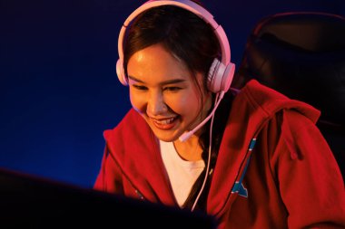 Portre sunucusu güzel Asyalı kız flamasının çevrimiçi oyun oynaması kulaklık takması pastel renkli konuşmalar izleyici medyası ile çevrimiçi. Esport yetenekli takım oyuncuları neon mavi odada. Taktik.