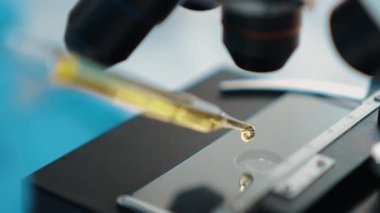 Bilimsel laboratuar araştırmacısı mikroskobik slayt üzerine sıvı örneği bırakır. Tıbbi muayene için ya da yeni teşhis aleti için. Mikrobiyolog ya da tıp çalışanı laboratuarda deney yapıyor. Ağır çekim. Katı.