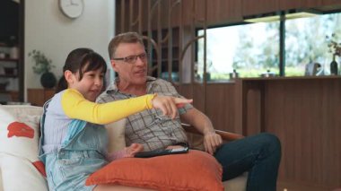 Grandfather and granddaughter eat french fries watch interesting entertainment on TV. Senior use technology communicate with young generation cross generation gap strengthen family bond. Divergence.