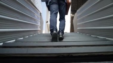 Merdivenlerden çıkan başarılı iş adamının bacağına yakın plan. Müdürün iş yerini değiştirmesi, yeni bir şey keşfetmesi, gelişmesi, terfi etmesi ya da gün ışığına çıkması. Yükseliyor. Bacağa odaklan. Sevinçli..