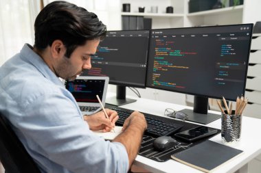 Akıllı IT geliştiricisi laptop ve iki pc ekranda kodlanan kağıtlar üzerine veri notları yazarak modern ofiste uygulama programı güncelleme sürüm sistemi yaratıyor. Tahmin et..