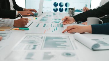 Modern bir ofis ortamında tablo üzerinde grafikler ve grafiklerle veri analizi yapan dinamik bir iş toplantısı. SACTR