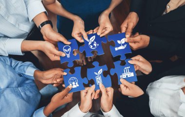 Bu görüntü, sürdürülebilirlik, yenilik ve çevresel sorumluluğu sembolize eden bulmaca parçalarını birleştirmek için bir araya gelen çeşitli elleri yakalar. Dostluk