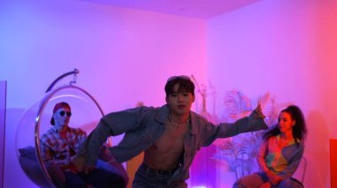 Çok kültürlü bir arkadaş kürsüde otururken Asyalı yetenekli bir dansçı modern müziğe geçiyor. Profesyonel dansçı, hipster takımı tezahürat yaparken ve desteklerken enerjik adımlar atıyor. Mutluluk.