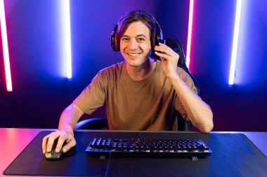 Kazanmak için çevrimiçi oyun oynayan akıllı flama makinesinin sunucu kanalı, neon ışıklı odada seçilen takım yarışması için izleyicilerle birlikte canlı yayında canlı yayında kulaklık takıyor. Bireysel.