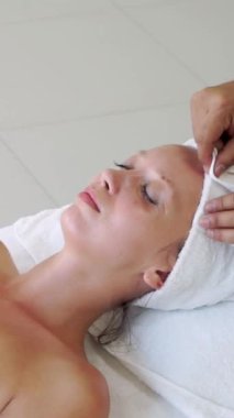 Spa yatağında uzanan rahat genç bir kadın lüks bir spa merkezinde yüz bakımı ve masaj için hazırlandı. Sağlık, stres atma ve gençleştirme kavramı.