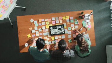 Toplantı masasında renk paletleriyle birlikte yapışkan notlar kullanarak yaratıcı tasarımcının beyin fırtınası fikrinin üst görüntüsü. Akıllı takımın hava görüntüsü tabletten simge grafiği seçiyor. Sempozyum.