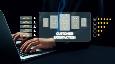 Bir iş adamı, profesyonel bir ortamda modern değerlendirme uygulamalarını tasvir ederek, dizüstü bilgisayardaki yıldız reytingleri ve geri bildirim formlarını kullanarak müşteri memnuniyetini analiz eder. Dörtgen