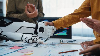 Bir insan ve robot modern bir çalışma alanında el sıkışıyor, iş dünyasındaki işbirliğini ve yenilikçi teknolojiyi grafikler ve veri analiz elementleri arasında sergiliyor. Noogenesis