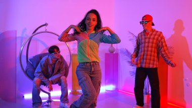 Çekici mutlu dansçı kameraya bakarken zeki kadın neon ışıkla kafiyeli hareket ediyor. Profesyonel İspanyol şarkıcı çeşitli arkadaşlarıyla renkli kıyafetler giyerken break dans yapıyor. Mutluluk.