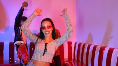 Çok kültürlü bir arkadaş birlikte dans ediyor ve hiphop müziği eşliğinde restoranda ya da kafede pembe neon ışıklı duruyor. Profesyonel sokak dansçıları grubu enerjik hareketler sergiliyor. Mutluluk.