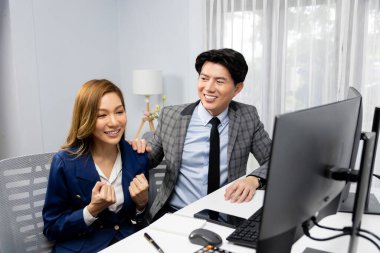 Başarılı gülümseyen Asyalı iş ortakları borsa veritabanında kârlı bir proje için el ele tutuşuyorlar. Yan görüntüdeki modern ev ofisinde resmi takım elbise giyiyorlar. İnfobahn.