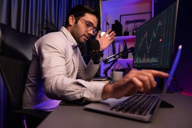 Akıllı tüccar işadamı, karanlık oda gecesinde neon ışıklı ofisteki arama pazarında yüksek kârla ekranda bilgisayar ve bilgisayar üzerinde dinamik borsa yatırımları üzerinde yoğunlaşıyor. Tahmin et..