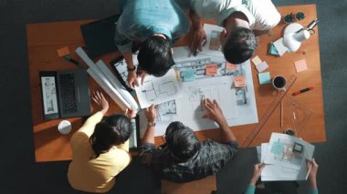 Yöneticinin proje planı yazması ve toplantıda oturması. Bilgisayarlı ve teçhizatlı ev inşaatı hakkında planlar yapan ve paylaşan iş adamlarının havadan görüşü. Sempozyum.