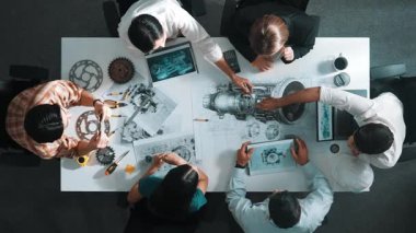 Türbin motoru tasarlamak için çalışan akıllı mühendis takımının yukarıdan aşağıya hava görüntüsü. Profesyonel teknisyen jet motoru yapımını tartışırken motorun bir kısmını işaret ediyor. Hizalama.