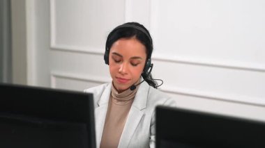 İş kadını kulaklık takıyor ve uzaktan müşteri ya da iş arkadaşını desteklemek için ofiste çalışıyor. Çağrı merkezi, tele pazarlama, müşteri destek acentesi telefon görüntülü konferans görüşmesi için hayati önem taşıyor.
