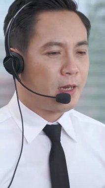 Kulaklık takan bir iş adamı ofiste çalışıyor. Arama merkezi, tele pazarlama, müşteri destek acentesi telefon görüşmesinde hizmet sunar.