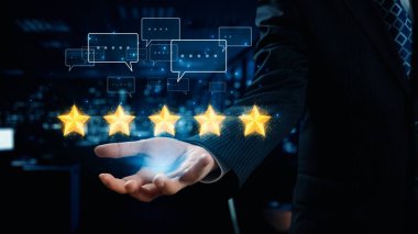 Bir işadamı, dijital iletişim baloncukları arasında başarıyı ve olumlu geri bildirimi simgeleyen ve modern iş kavramlarını gösteren beş yıldızlı bir nota doğru elini uzatıyor. Dörtgen