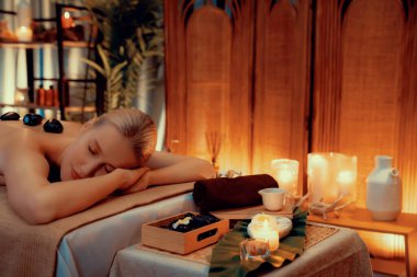 Lüks tatil köyündeki kaplıcalarda sıcak taş masajı, sıcak mum ışığı, spa bazalt taşı masajının keyfini çıkaran mutlu kadın müşteriler, rahatlatıcı bir sıcaklıkla vücudun üzerinde süzülüyorlar. Sessiz.