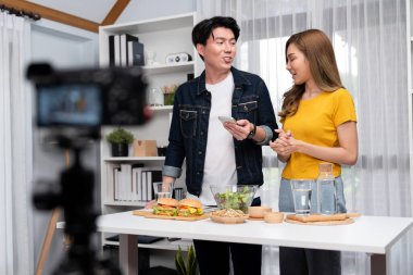 Aşçılar, sosyal medya yemek programı kanalı canlı yayın menü yemeği salatası, kepekli çörek ve video kameradan hamburger kaydı için telefonda yorum okuyorlar. İnfobahn.