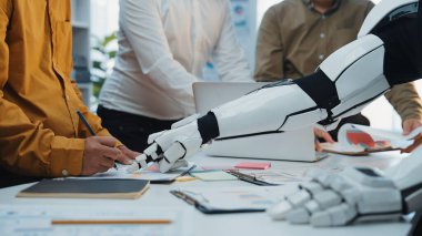 İnsanlar ve robotlar arasında canlı bir ofis sahnesi, araçlar ve yaratıcılıkla dolu modern bir çalışma alanında teknoloji ve yeniliğin altını çiziyor. Noogenesis