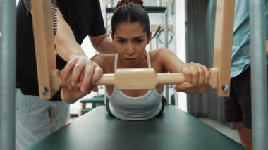 Pilates Cadillac masasında bar tabanlı bir alıştırmada bir müşteriye yardım eden eğitmen. Cadillac 'ta kuğu dalışı yapan kadın beden gücünü ve beden eğitimini arttırıyor. Alışkanlık.