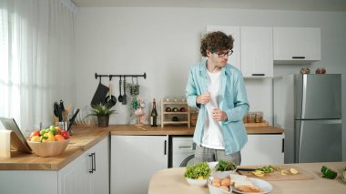 Mutlu baba yemek pişirirken müziğe geçiyor ve modern mutfakta öğle yemeği hazırlıyor. Aktif baba, sebze ve mutfak gereçleri ile çevrili sağlıklı yemek ya da salata yaparken şarkıyla dans ediyor. Pedagoji.