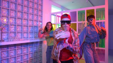 Değişik takımlarla dans ederken süslü gözlük takan yakışıklı hippi serbest stil müzikle mutlulukla dans ediyor. Beyaz hipster kulüpte parlak neon ışıkta sokak dansı yapıyor. Mutluluk.