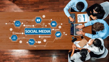 Çeşitli bir ekip, dizüstü bilgisayarlar ve dijital platformlardaki bilgi grafikleri ve veri analizleri yoluyla sosyal medya stratejilerini analiz ederek çağdaş bir ofis ortamında işbirliği yapıyor. Dostluk