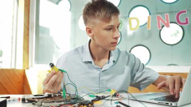 Akıllı mutlu çocuk araba modelini tamir etmek için elektronik alet kullanmayı öğreniyor ya da inceliyor. Lise öğrencisi STEM sınıfında otururken robotik makineleri tamir etmek için elektrikli teçhizat eğitimi alıyor. Öğretim