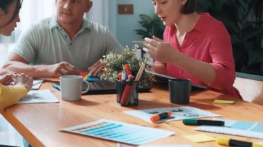 Renk paletinden renk seçmek için birlikte çalışan iş adamlarının en üst görüşü. Proje yöneticisi, logo grafiklerine bakarken pazarlama ekibine tablet kullanarak fikir sunuyor. Sempozyum.