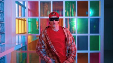 Serbest stil tişört giyerken sokak müziği çalan mutlu hipster. Gece kulübünde neon ışıkla dururken çekici break dansçı dans ve hareketli hareketler yapıyor. Mutluluk.