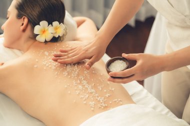 Lüks spa salonlarında sıcak mum ışığında cilt bakımı yaptıran kadın müşteri. Sağlık Spa vücut fırçasında tuz temizleme güzellik tedavisi. Sessiz.