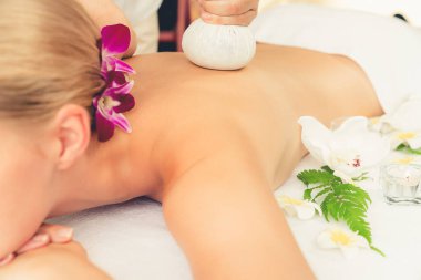 Sıcak bitkisel top spa masaj vücut tedavisi, masör kadın vücuduna nazikçe şifalı bitki torbası bastırıyor. Aromaterapi dinlenme sükuneti ve sükuneti kaplıca salonundaki atmosferi aydınlatıyor. Sessiz.