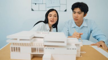 Becerikli mimari mühendisi ekip ölçümü ve ev modeline birlikte çalışırken karar verme ve toplantı odasındaki bina yapısı ve planlarla ilgili tartışmalar. Tertemiz..