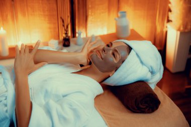 Kaplıca salonunun sakin atmosferi, üst düzey kadın müşteri sıcak mum ışığında kömür kömürü yüz kremi masajıyla kendini yenilemeye çalışıyor. Yüz bakımı ve güzellik konsepti. Sessiz.