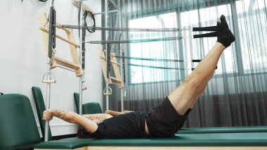 Bir grup müşteri, çekirdek dayanıklılığını ve bacak bağını geliştirmek için Cadillac reformatör makinesinde pilates egzersizleri yapıyor. Sağlıklı müşterilerin daha düşük poz verip kaldırma pozlarının üst görüntüsü. Sağlıklılık. Alışkanlık.
