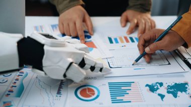 Bir insan ve bir robot bir iş toplantısında çeşitli grafik ve grafikleri analiz ederek işbirliği yaparlar. Bu görüntü takım çalışmasının ve karar verme mekanizmasındaki yeniliğin geleceğini temsil ediyor. Yaratıcılık