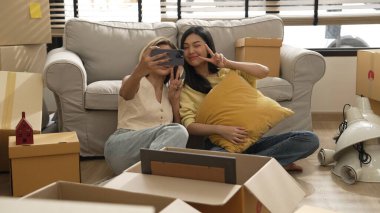 Kız arkadaş taşınma gününde oturma odasında otururken fotoğraf çekiyor. Çekici bir çift, karton kutuyla çevrili kanepede yatarken birlikte vakit geçiriyor. Yeniden yerleştirme ve ilişki. Myrmidon.