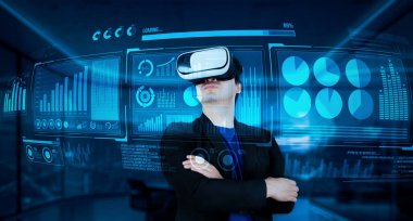 VR gözlüklü proje yöneticisi mali tabloya bakıyor ve ofiste mavi ışık parlıyor. Yetenekli iş adamı artırılmış gerçeklikten elde edilen verileri kullanarak pazarlama stratejisini kontrol edip planlıyor. Yaratıcılık.