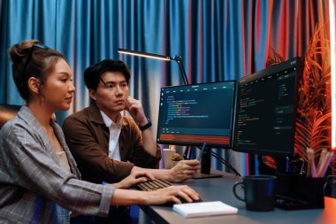 Bilgi teknolojisi geliştiricileri modern ofisteki neon ışık odasında verileri çevrimiçi olarak çalıştıran akıllı web sitesi geliştirme kodlayıcı sistemine işaret ediyorlar. İnfobahn.