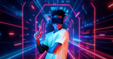 VR gözlüklü profesyonel erkek oyuncu parlayan neon ışıkla oyun oynuyor. Heyecanlı oyuncu artırılmış gerçeklik teknolojisi yeniliklerini kullanarak metaevrene bağlanmayı seviyor. Yaratıcılık.