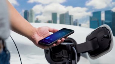 EV akıllı telefon uygulamasında EV akü durumu. Kamu şarj istasyonundan şarj olurken. EV arabaların yenilikçi teknolojik gelişimi ve alternatif enerji kullanımı. İnceleyin