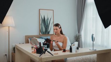 Sosyal medya için güzellik ve kozmetik video içeriği hazırlayan genç bir kadın. Güzellik blogcusu kameraya gülümserken seyircilere ve takipçilere güzellik bakımını gösteriyor. Düzenle