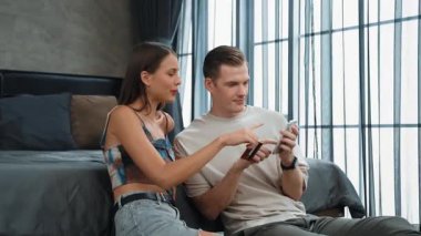 Genç çift, kredi kartıyla ödemek için internet üzerinden ödeme uygulaması ve dijital cüzdan kullanarak yatak odasında oturuyor. Mobil internet üzerinden alışveriş ve modern alımlar. Düzenle