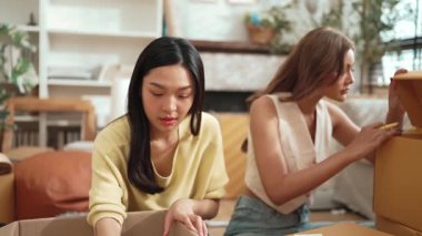 Çekici bir oda arkadaşı oturma odasında paket paketlerken pakette konum yazıyor. Mutlu satıcı birlikte çalışıyor ve teslimat paketini hazırlıyor. Girişimci kargo kutusu paketliyor. Myrmidon.