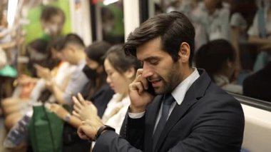 Gülümseyen akıllı erkek yatırımcı, proje hakkında telefonla müdürle konuşuyor. Kafkasyalı mutlu iş adamı trende otururken terfi ettiği için iyi haberler alıyor. Toplu taşıma. Sevinçli..